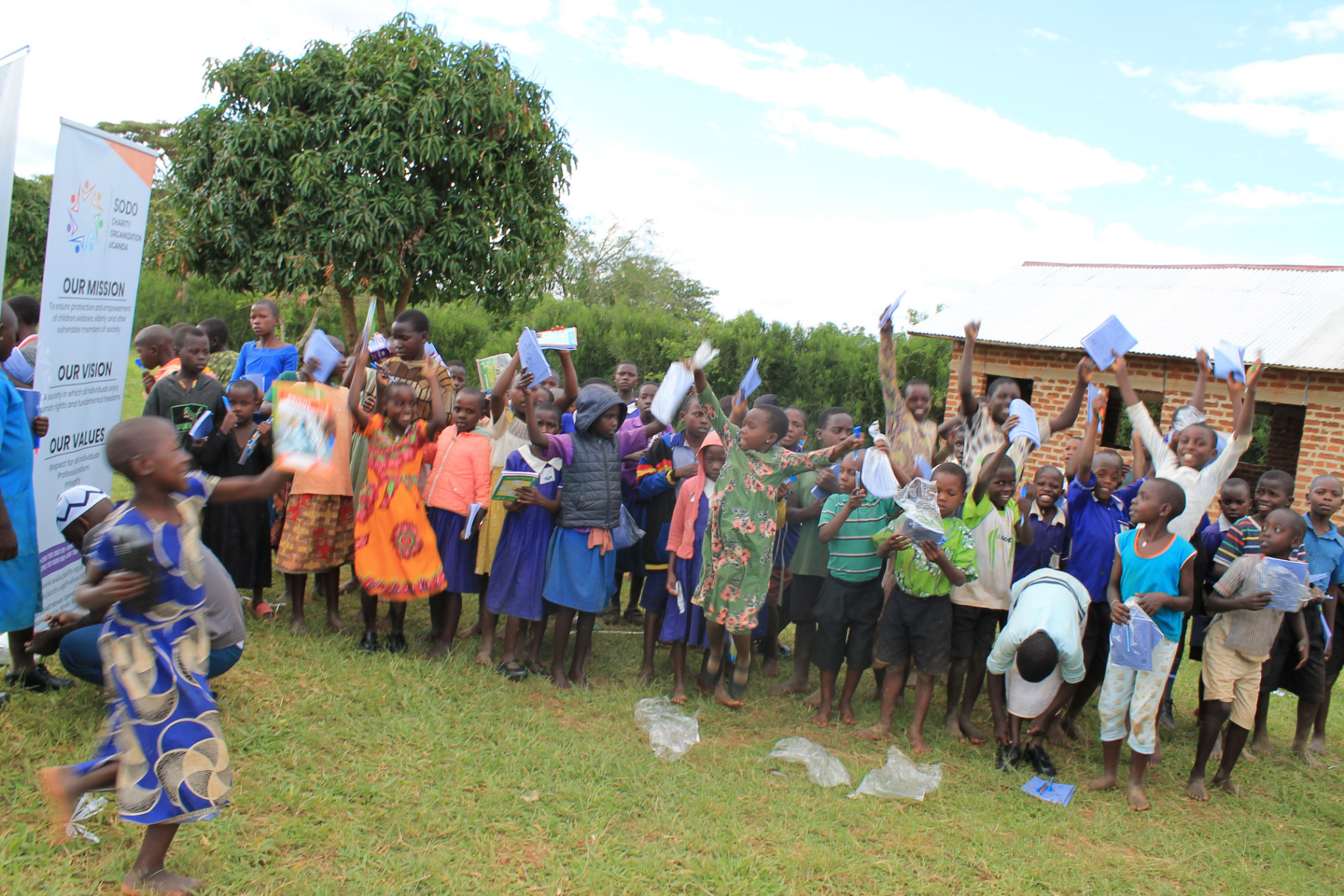 Ugandan schoolchildren holding books received from SODO Charity